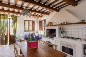 una cocina con una mesa de madera con flores púrpuras. en Casale Oliva in a landscape of oaks, olive e cherry trees, en Santa Vittoria in Matenano