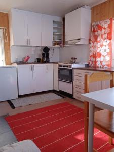 cocina con armarios blancos y alfombra roja en Riverside Restplace, en Tornio