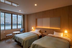 Habitación de hotel con 2 camas y ventana grande. en Kurobe View Hotel, en Omachi