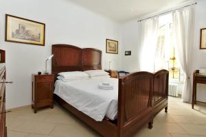 Cette chambre comprend un lit avec des draps blancs et un mobilier en bois. dans l'établissement Roma Borgo91, à Rome