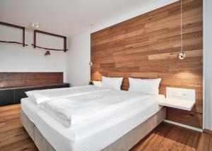 a bedroom with a large white bed with a wooden wall at WaldFunkeln LODGE in Hinterzarten