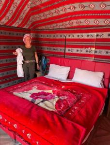 a woman standing next to a large red bed at Wadi rum Local guide camp in Wadi Rum