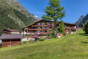 ein Hotel in den Bergen mit grünem Rasen in der Unterkunft Hotel Sonnblick in Sankt Leonhard im Pitztal