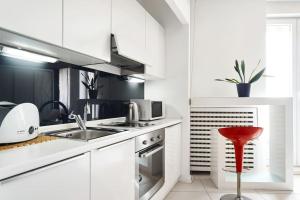 a kitchen with white cabinets and a red stool at Irundo Downtown Apartments in Zagreb
