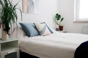 Un dormitorio con una cama blanca con almohadas y una planta en Keba, en Władysławowo