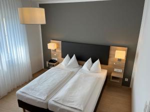 a bedroom with a bed with white sheets and pillows at Hotel Garni Geisler in Cologne
