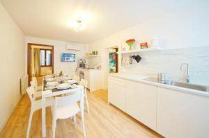a kitchen with white cabinets and a table and chairs at Calle dei Fabbri Apartment Marble in Venice