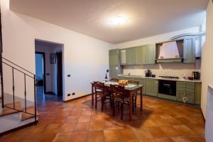 a kitchen with green cabinets and a table with chairs at Tognazzi Casa Vacanze - Casa Vico in Zambra