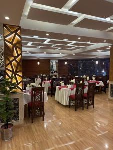 un comedor con mesas y sillas en un restaurante en Grand Mongolia Hotel, en Rawalpindi