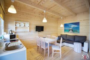 a kitchen and living room with a table and a couch at Morska Fala Domki in Pobierowo