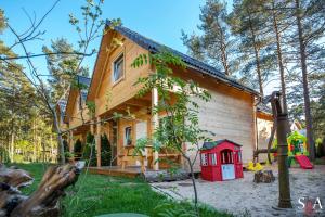a house with a red dog house in the yard at Morska Fala Domki in Pobierowo