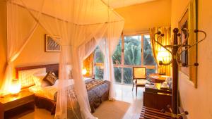 Humura Resorts في كامبالا: غرفة نوم مع سرير مظلة مع نافذة