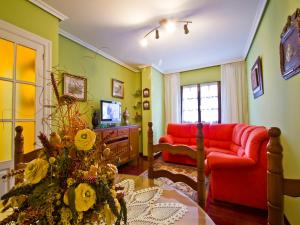 a living room with a red couch and a television at Apartamento EL RINCON DE MARIA in Santillana del Mar