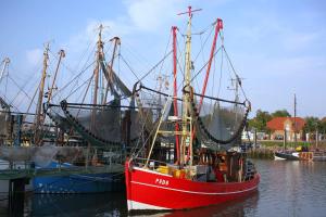 Ein rotes Boot sitzt im Wasser in der Unterkunft Gästehaus Küste in Nordenham