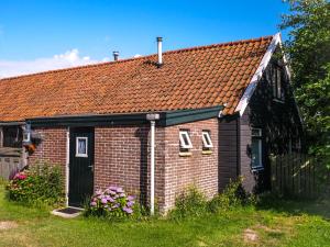 een klein bakstenen huis met een rood dak bij Eb in Callantsoog