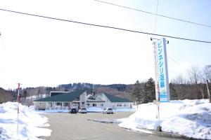 een met sneeuw bedekte straat met een bord voor een gebouw bij ピンネシリ温泉望岳荘 