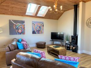 a living room with a couch and a television at Partridge Lodge with Hot Tub in Forgandenny
