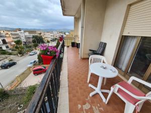 einen Balkon mit einem weißen Tisch und Stühlen sowie einer Straße in der Unterkunft Sole Gibellina in Nuova Gibellina