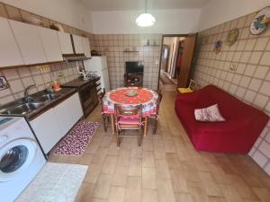 eine kleine Küche mit einem Tisch und einem roten Sofa in der Unterkunft Sole Gibellina in Nuova Gibellina
