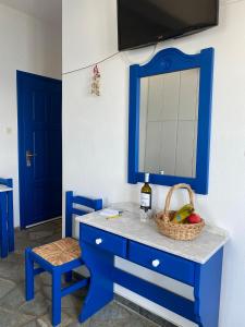 a blue dresser with a basket of fruit and a mirror at Cavos Studio by the sea in Drios