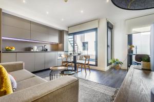 una cucina e un soggiorno con divano e tavolo di Precioso Ático de diseño, gran Terraza y Garaje en pleno centro a Siviglia