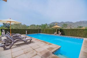 a swimming pool with lounge chairs and an umbrella at Can Pansa in Port de Pollensa