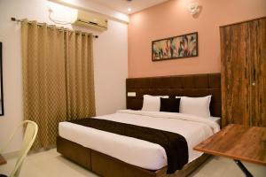 a bedroom with a large bed and a table at Xcel Luxury Hotel Apartments-Home Living Redefined in Mysore