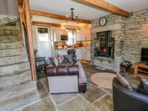 a living room with two chairs and a stone fireplace at Ducking Well Cottage in Keighley