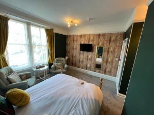 a bedroom with a bed and a chair and a television at Kirkwood Guest House in Windermere