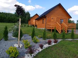 una cabaña de madera con un jardín frente a ella en Agroturystyka Sosenka, en Bieliny