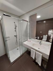 a bathroom with a glass shower and a sink at Hotel Monte Lírio in Espinho