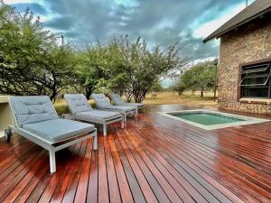 a deck with three chairs and a swimming pool at Nghala Self-catering Holiday Home in Marloth Park