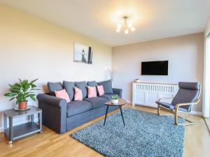 a living room with a blue couch and a tv at Flat 19 By The Beach in Harwich