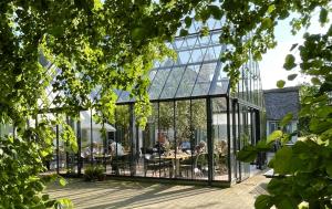 a glass house with people sitting at tables in it at Østergård Kultur B&B in Læsø