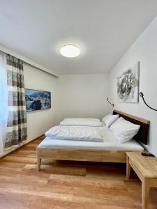 a white bedroom with a bed and a table at Kaiser-Franz in Bad Hofgastein