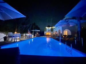 una piscina por la noche con sombrillas en Villa Calma - Vue Mer en Al Ḩaddādah