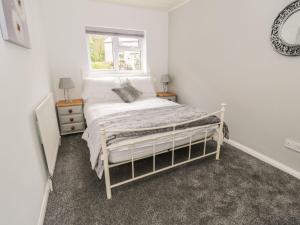 a white bedroom with a bed and a window at 4 Bronrallt in Penmaen-mawr