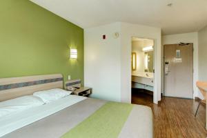 a bedroom with a bed and a bathroom with a sink at Super 8 by Wyndham Aurora East in Aurora +18 photos