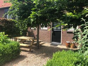 einen hölzernen Picknicktisch unter einem Baum im Hof in der Unterkunft B&B Helena's Hoeve in Buggenum