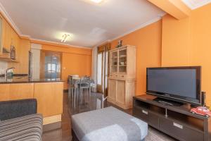 a living room with a flat screen tv and a kitchen at Confortable piso en Lekeitio, a 7 minutos de la playa in Lekeitio