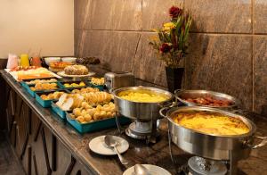 un buffet con muchos tipos diferentes de comida en una barra en Dayrell Hotel e Centro De Convenções, en Belo Horizonte