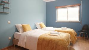twee bedden in een kamer met blauwe muren en een raam bij Terraço dos Rabujas in Nazaré