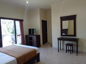 a bedroom with a bed and a mirror and a desk at Hotel Mawar Sari Mitra RedDoorz in Payangan