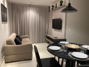 uma sala de estar com um sofá e uma mesa de jantar em APARTAMENTO MODERNO A 150m DA PRAIA DO CABO BRANCO em João Pessoa