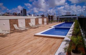 una terraza en la azotea con sillas y una piscina en un edificio en APARTAMENTO MODERNO A 150m DA PRAIA DO CABO BRANCO en João Pessoa