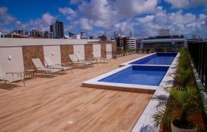 a rooftop deck with chairs and a swimming pool on a building at APARTAMENTO MODERNO A 150m DA PRAIA DO CABO BRANCO in João Pessoa
