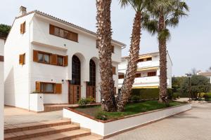 a white building with palm trees in front of it at La marinera Beach House in Platja  d'Aro