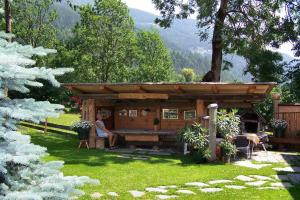 a woman sitting in front of a cabin in a yard at Ferienhaus Dummer in Flattach