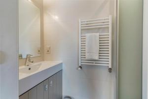 a white bathroom with a sink and a mirror at Duplex apartment with terrace - next to the beach in Knokke-Heist +14 photos