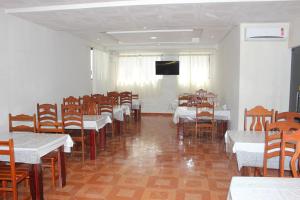 a dining room with tables and chairs and a television at Hotel Litoral in Aracaju